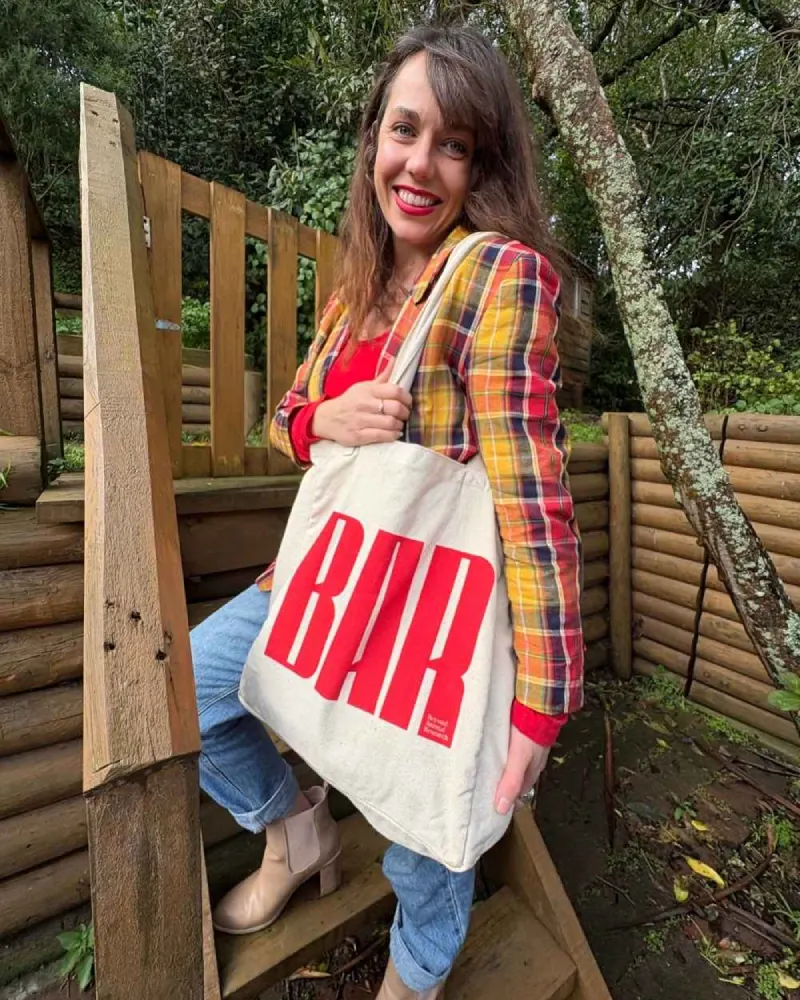 Person outdoors smiling while holding a Beyond Animal Research tote bag